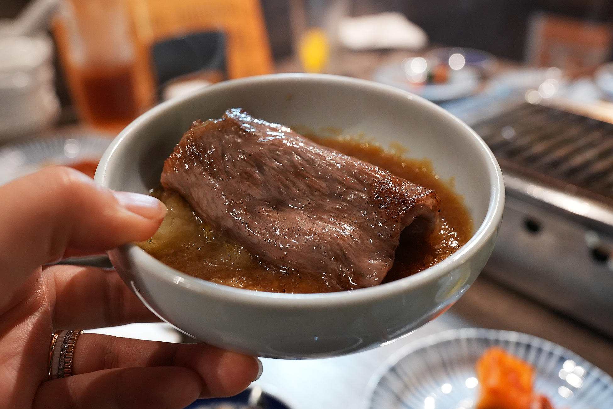 麻布苑の特選ロースを大根おろしのタレにつけているところ。焼いた肉を小鉢のタレにくぐらせている