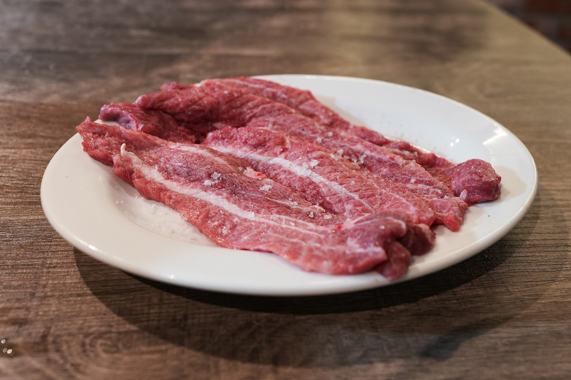 麻布苑のツラミ。細長くスライスされた頬肉が3枚、白い皿に粗塩をふって盛られている