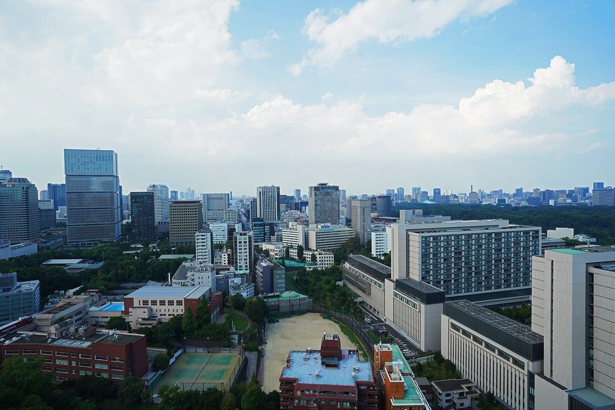 客室からの眺望。青空の下に都心のビル群と、右手に広がる緑