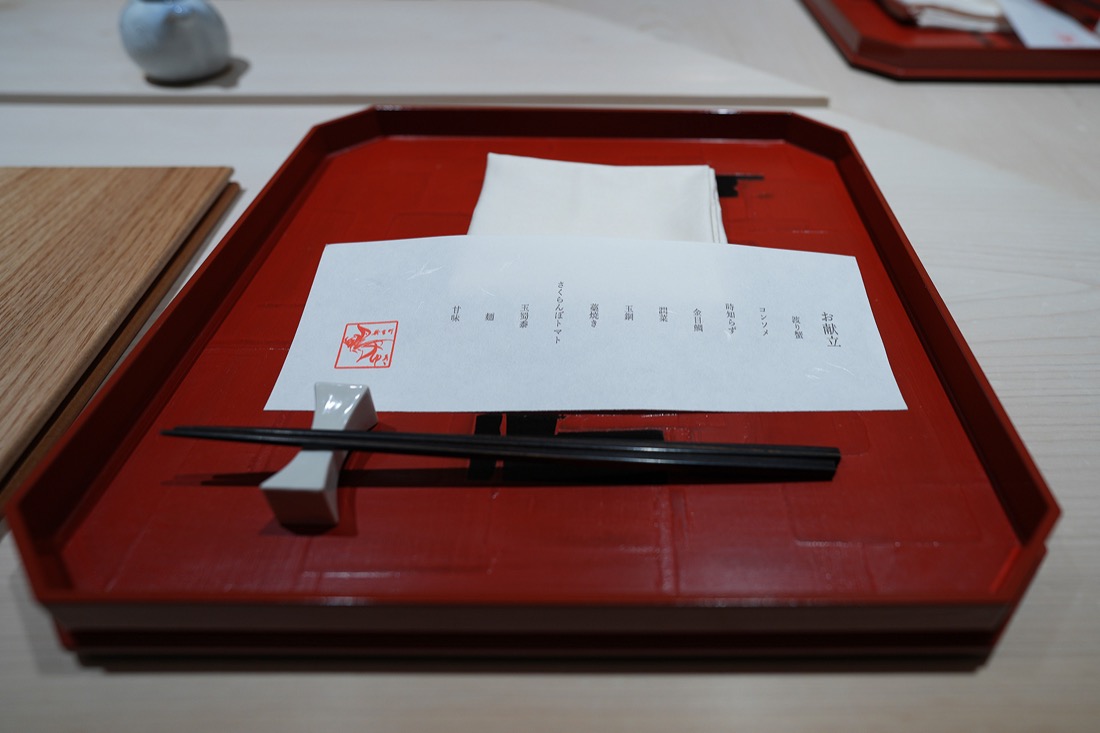 朱塗りの膳にのせられた、鴨ゆきのお献立の品書きと黒い箸