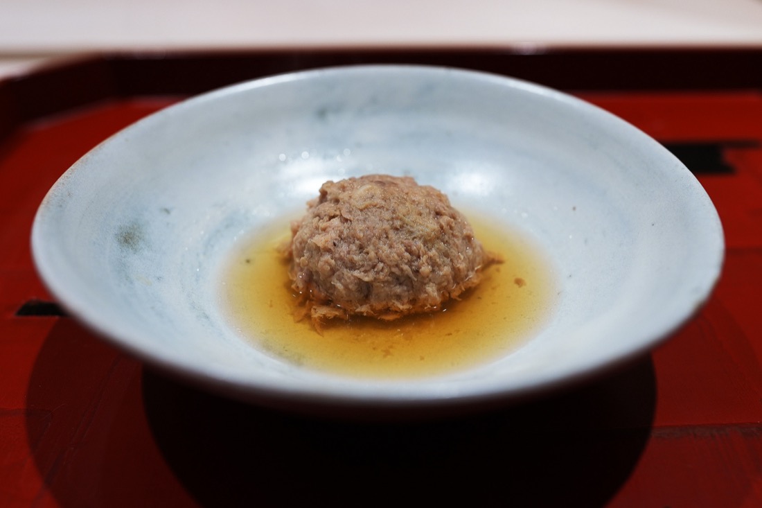 淡い色の鉢に、出汁を張って盛られた丸い鴨つくね