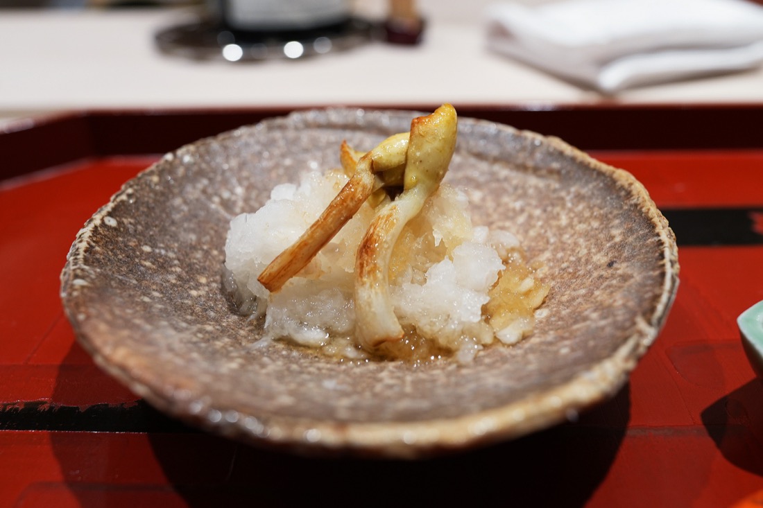 大根おろしの上にのせられた、焼いたピーナッツもやし。豆の部分がついている
