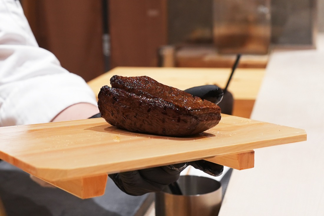 木のまな板にのせられた、藁焼きを終えた鴨のかたまり肉