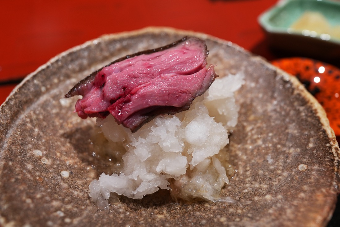 大根おろしの上にのせられた、藁焼きにした鴨のもも肉