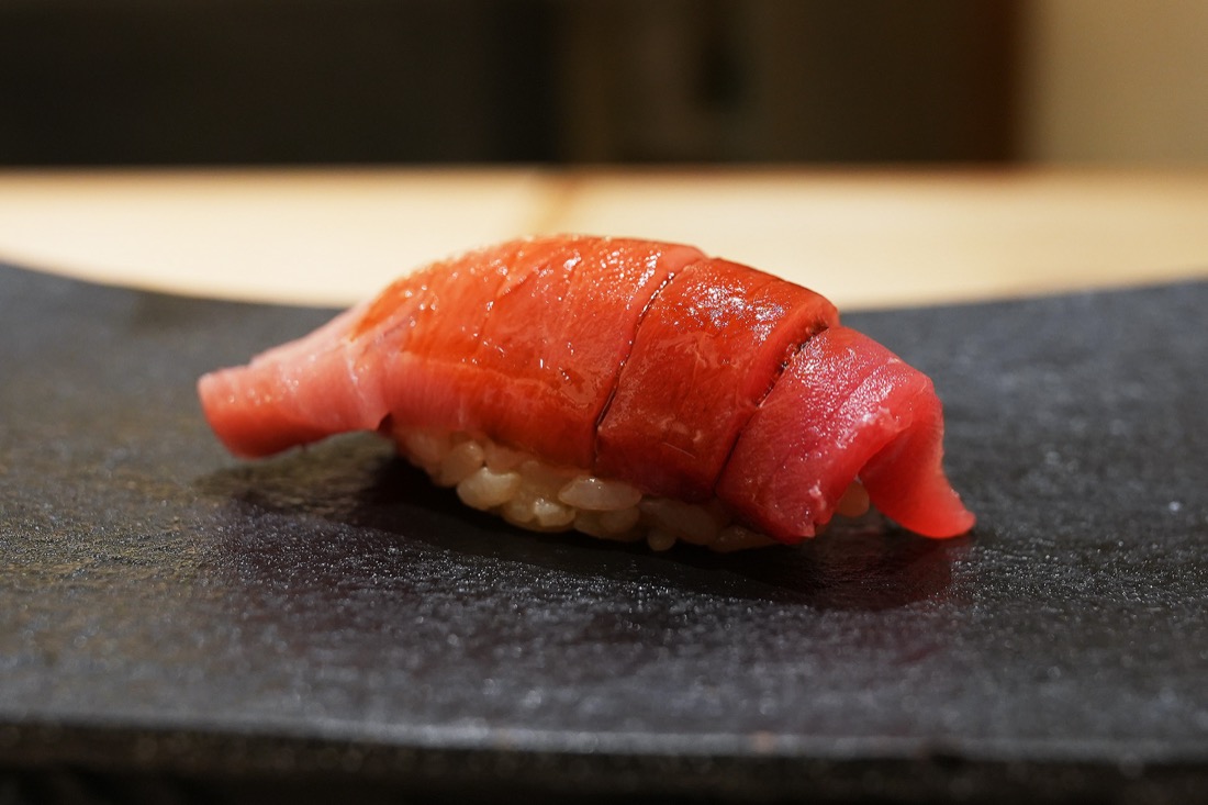 黒い付け台にのせられた、赤身と脂が混じる中トロの握り