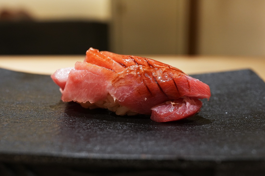 黒い付け台にのせられた、細かく包丁を入れた大トロの握り
