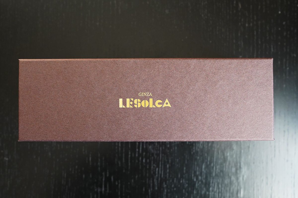 LESOLCAの贅沢チーズケーキが届いた箱。くすんだブラウンの化粧箱に金の箔押しでGINZA LESOLCAのロゴ