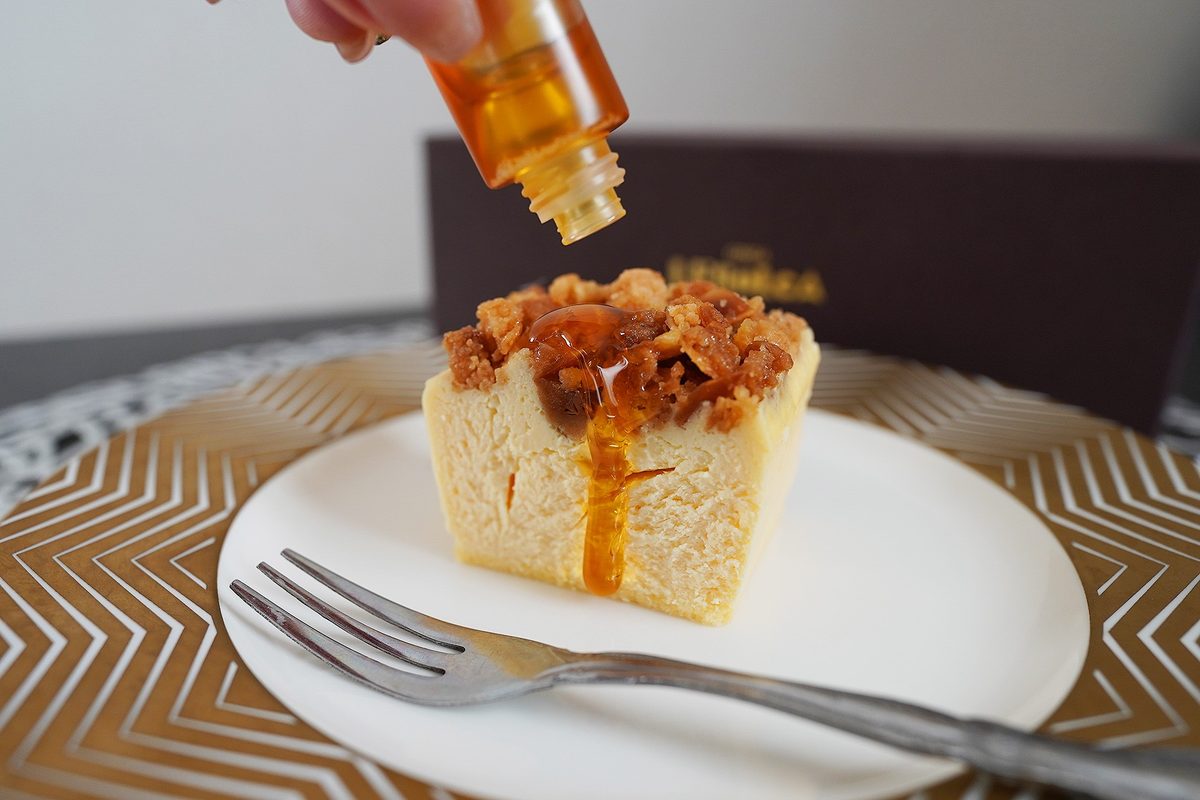 栗のはちみつをチーズケーキにかけているところ。琥珀色のはちみつが断面をつたう