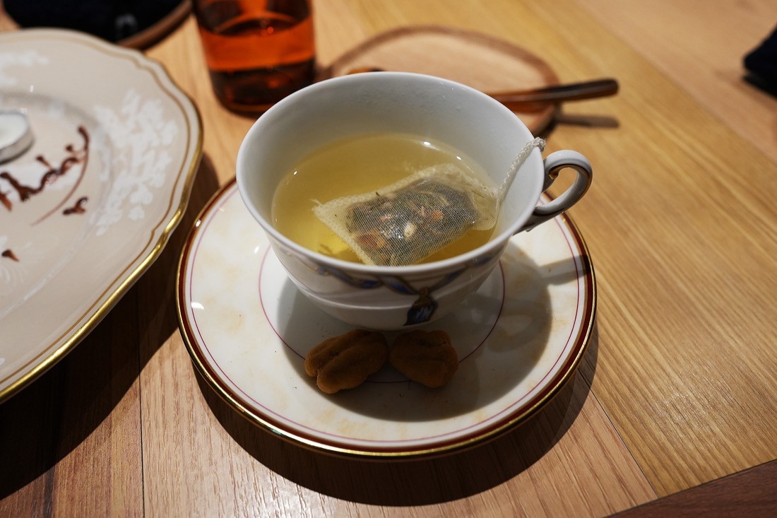 染付のカップに注がれたお茶と、受け皿にのった小さな菓子