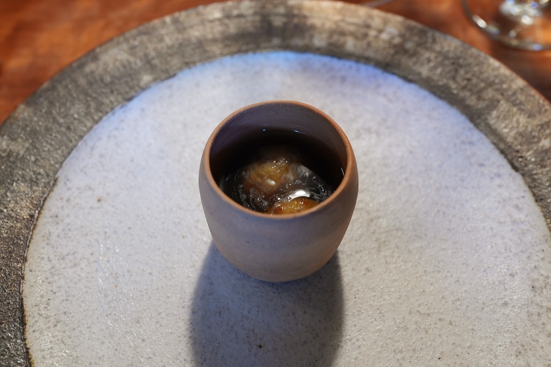 素焼きの器に注がれた、すっぽんと香茸の濃い色のスープ。揚げたニョッキが沈んでいる