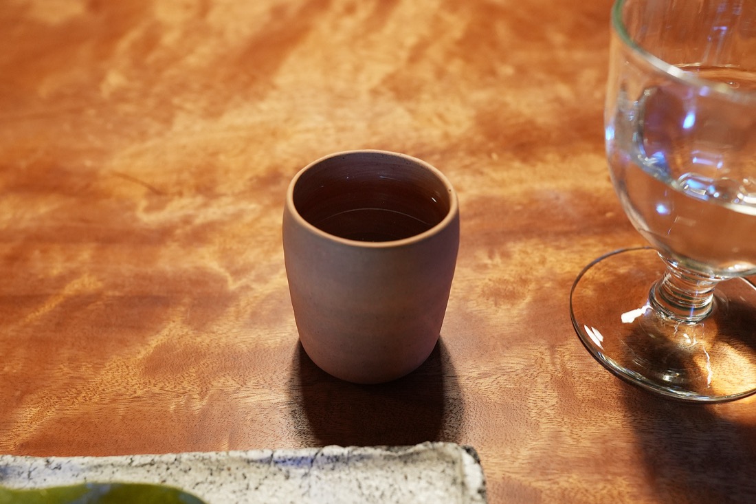 素焼きの湯呑みに注がれた、茶色い木蓮の発酵茶
