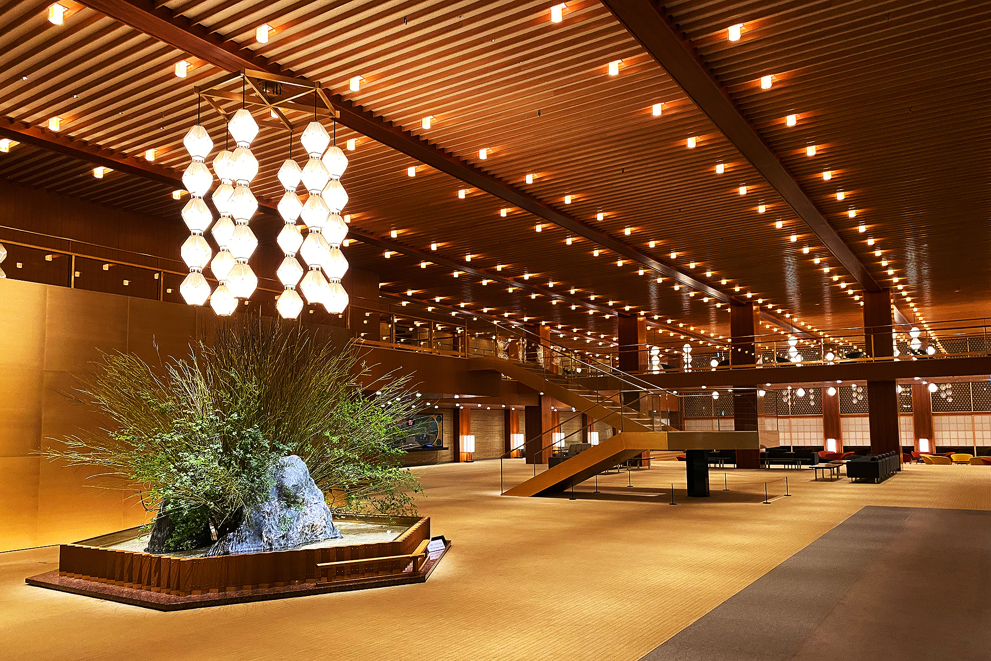 The Okura Tokyoのメインロビー。天井から連なるオークラ・ランターンが並び、奥に生け花が置かれている