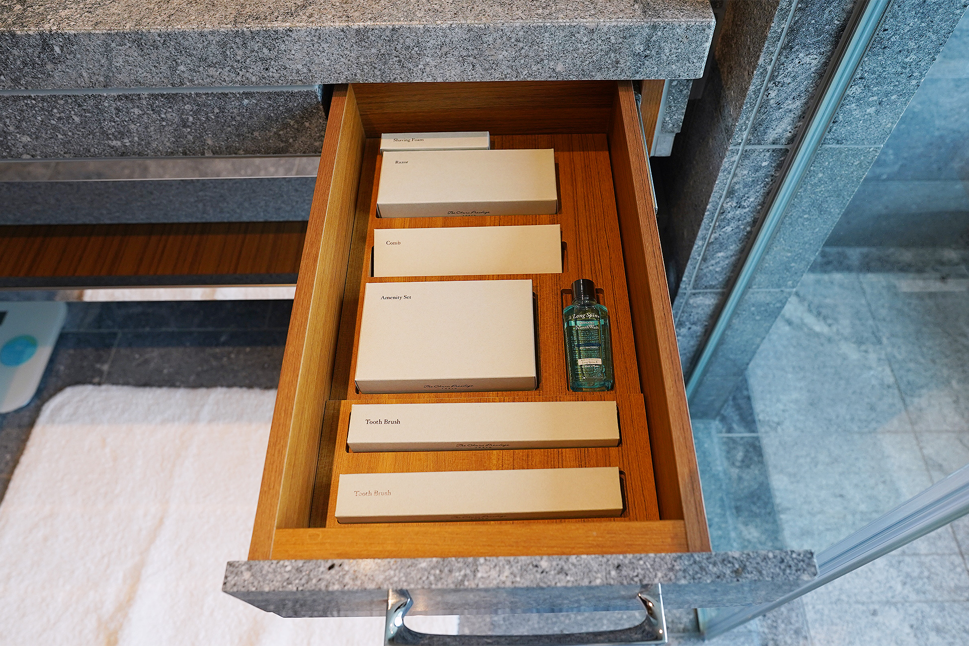 The Okura Tokyoプレステージルームの洗面台下の引き出し。シェービングフォーム、レザー、コーム、アメニティセット、歯ブラシの箱が仕切って並べられている