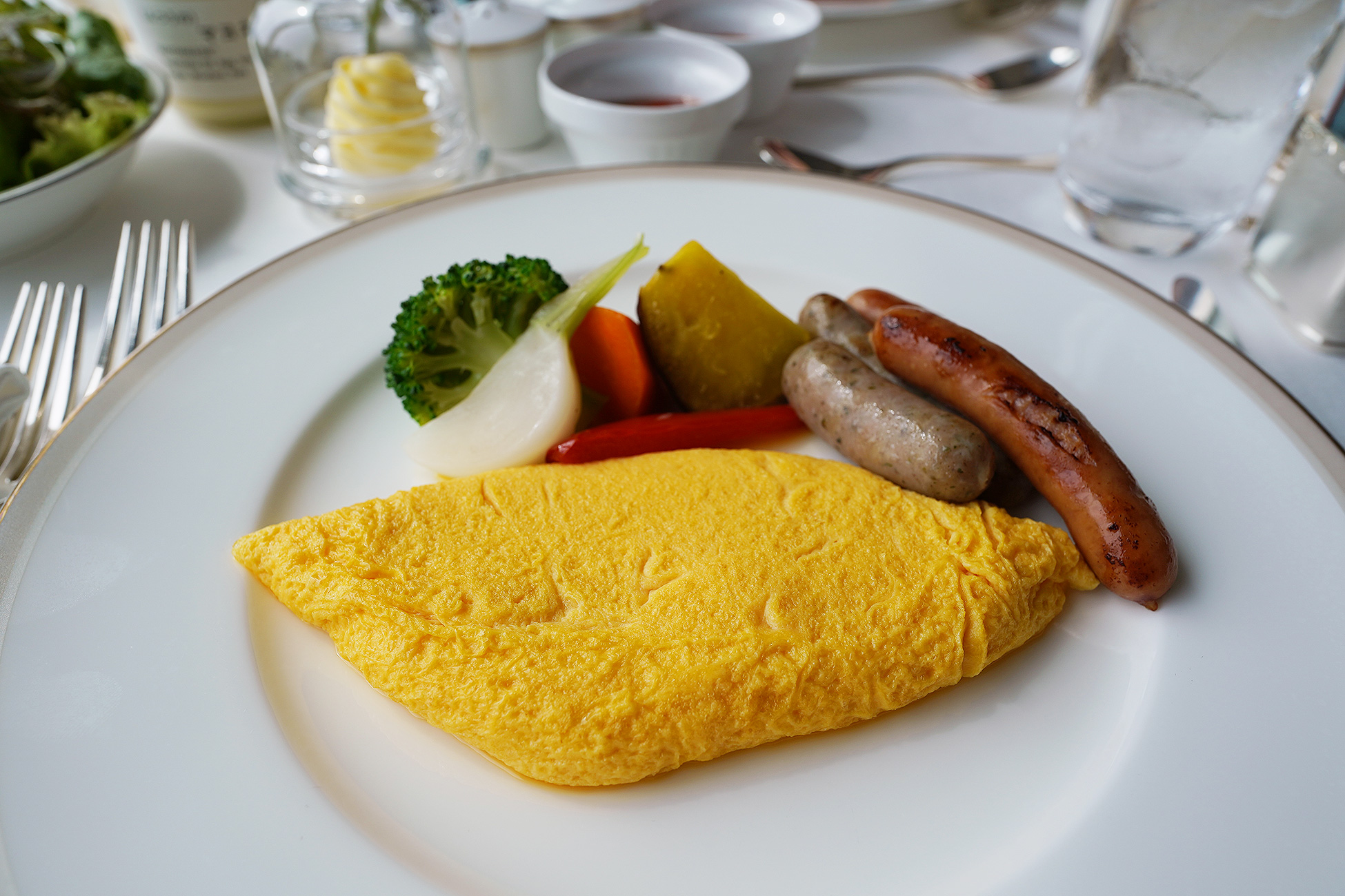 The Okura Tokyoのルームサービス朝食のオムレツ。きれいな楕円形に焼かれたオムレツにベーコンと温野菜が添えられている