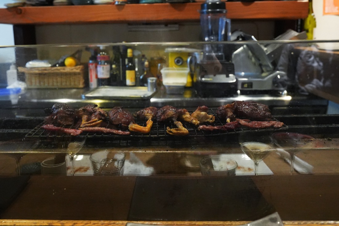 炭火の焼き台に、たくさんの串が並んでいるところ