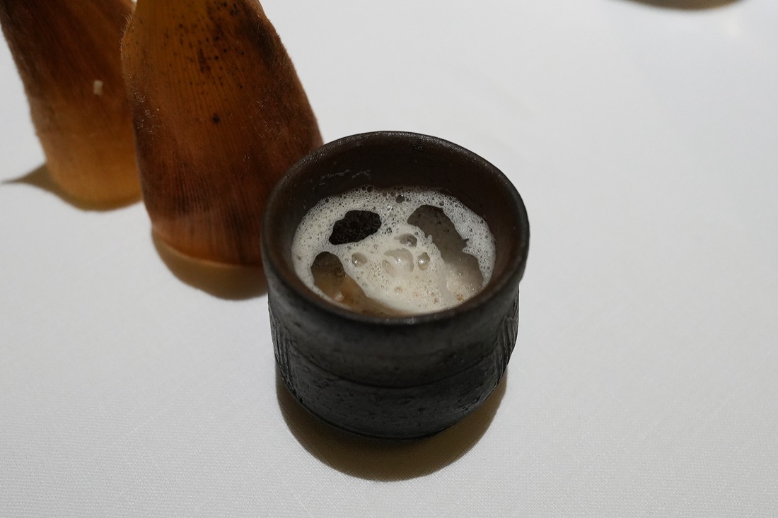 黒い焼き締めの器に注がれた、泡の浮いた温かなスープ