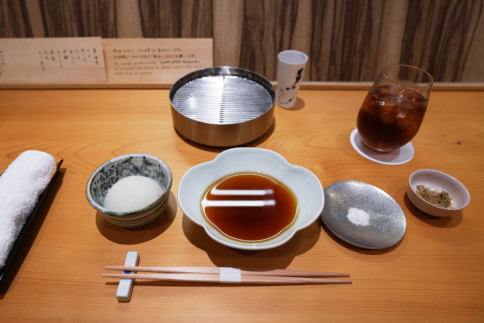 白木のカウンターに用意された天つゆ、大根おろし、塩、天ぷらを受ける金網の器