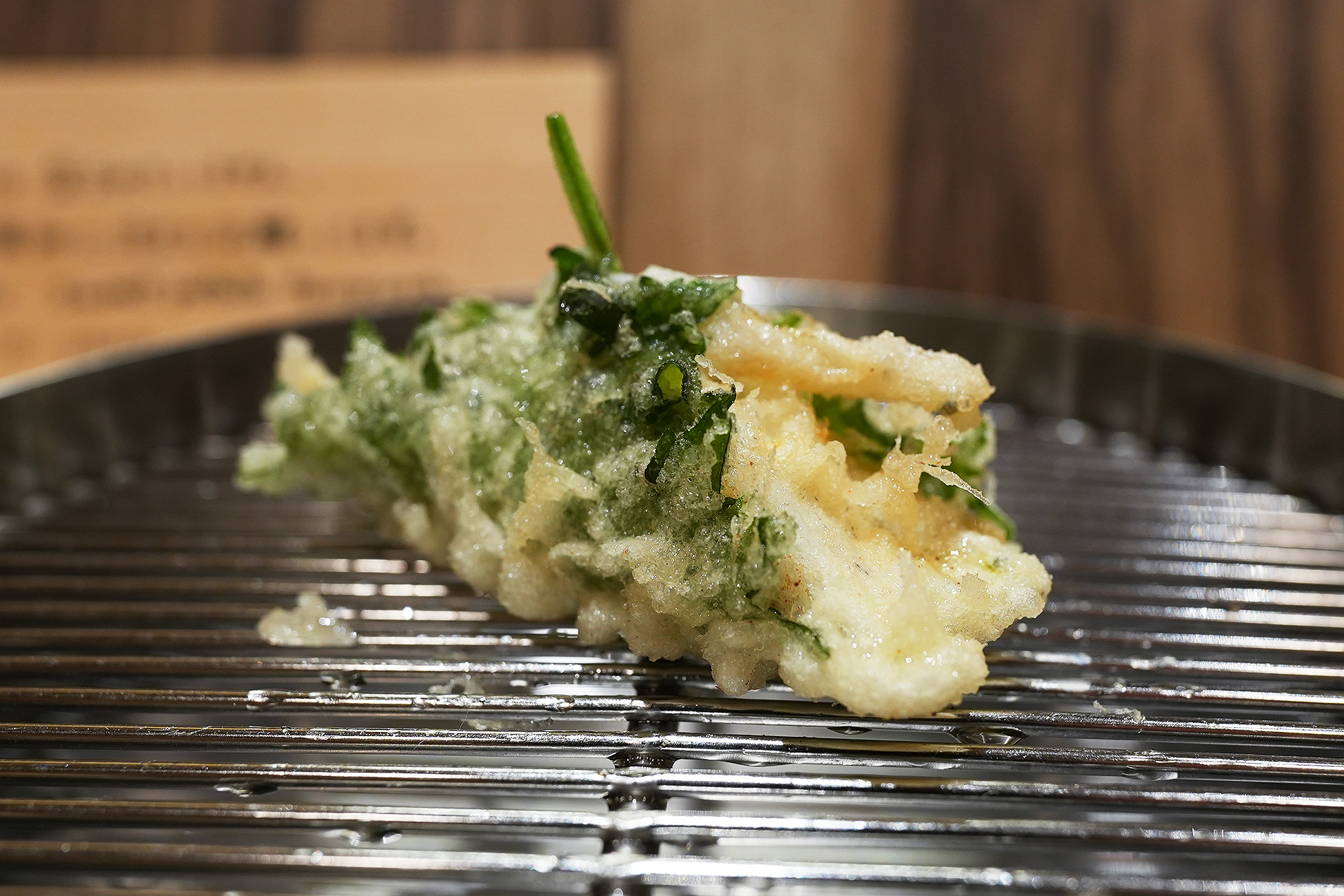 大葉でひとつにまとめて揚げた白魚の天ぷら。白い身と緑の葉が重なっている