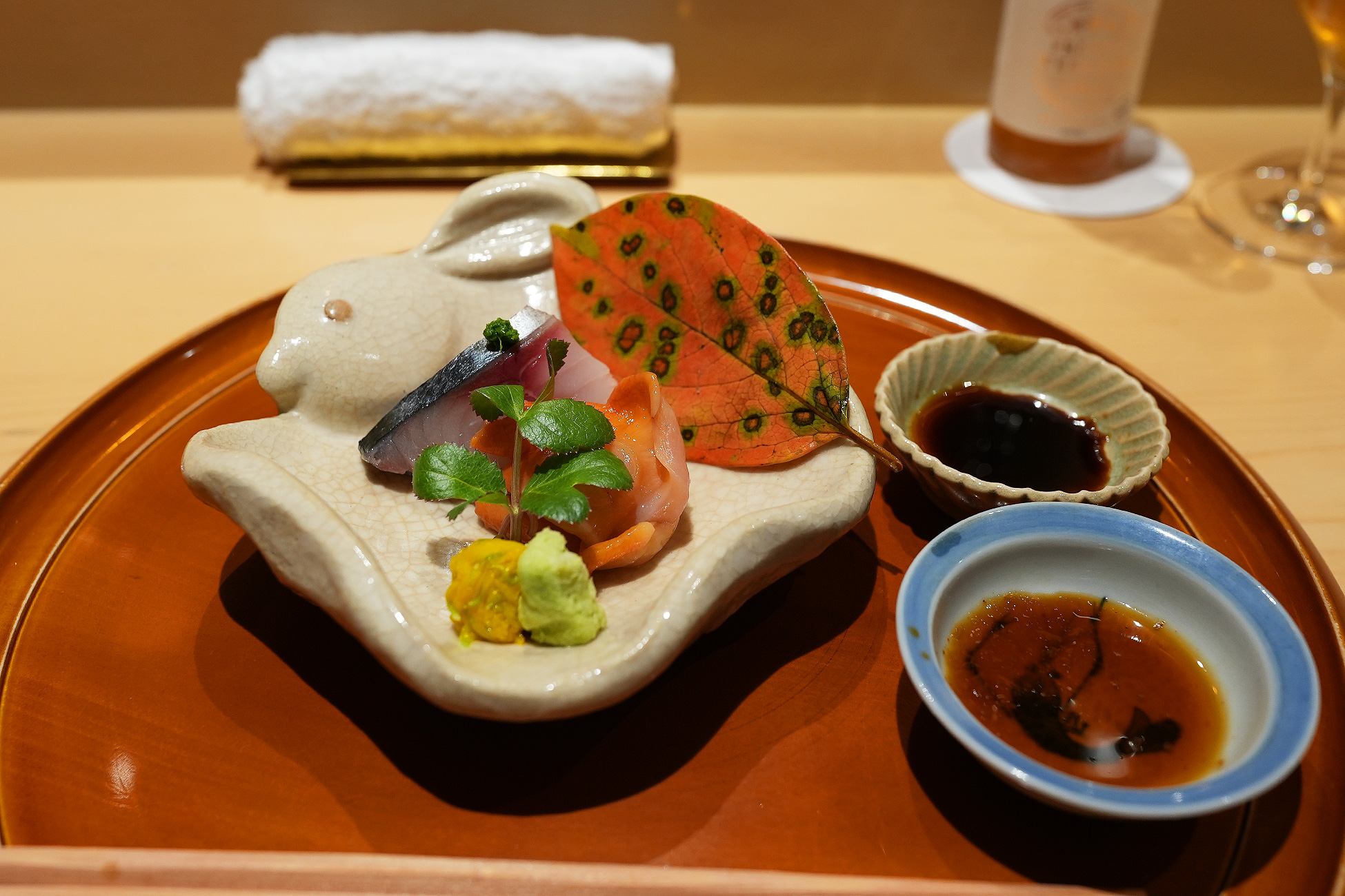 兎をかたどった白い器に盛られた鯖と赤貝のお造り。色づいた葉と山葵を添えて
