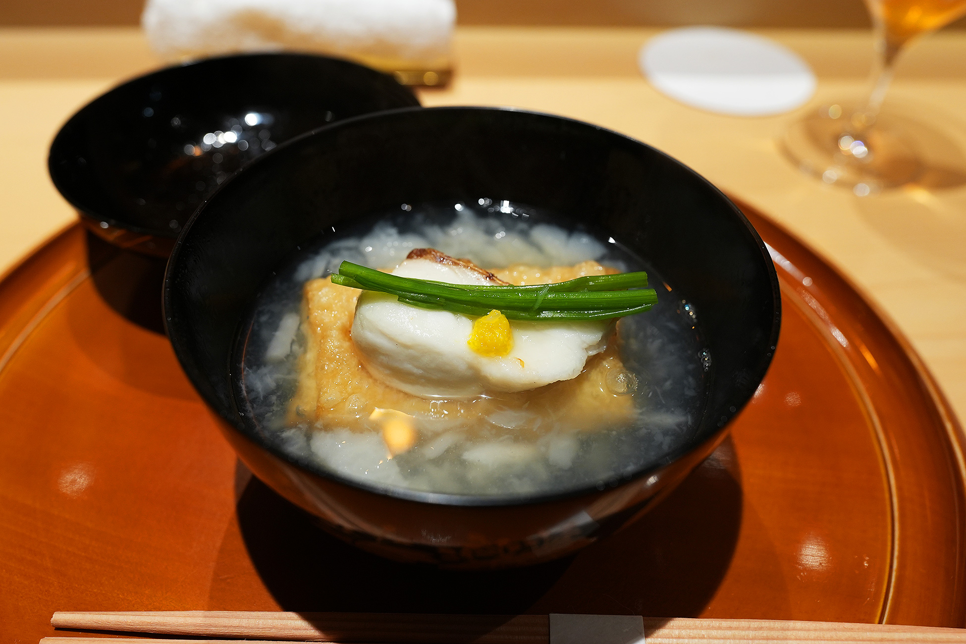 黒い椀に、焼いた真鯛と東寺湯葉、蕪のみぞれ仕立ての出汁