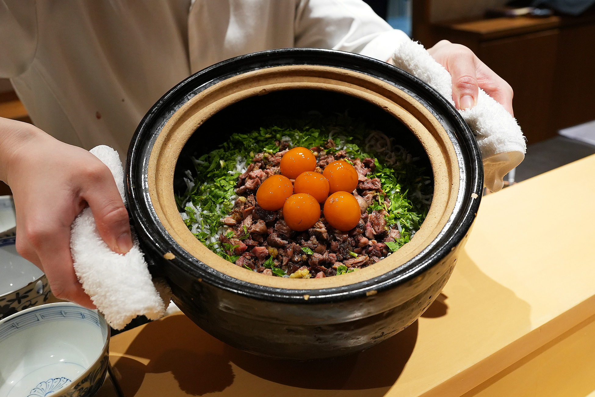 土鍋いっぱいの炊き込みご飯。焼いたすっぽんと刻んだ青菜の上に卵黄の醤油漬けが5つ並ぶ