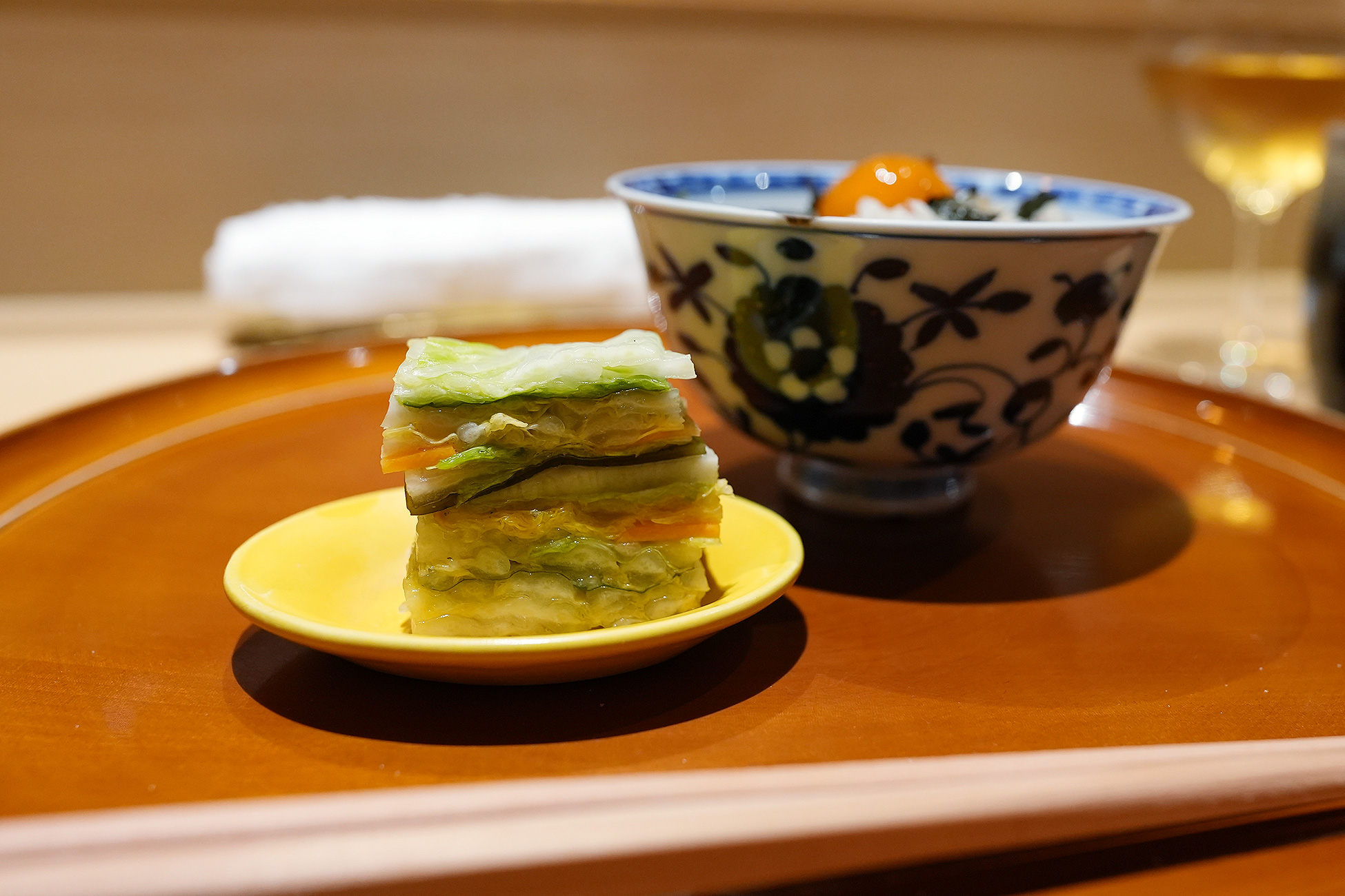 黄色い小皿にのせた重ね漬け。白菜、胡瓜、人参などを層に重ねて切ってある