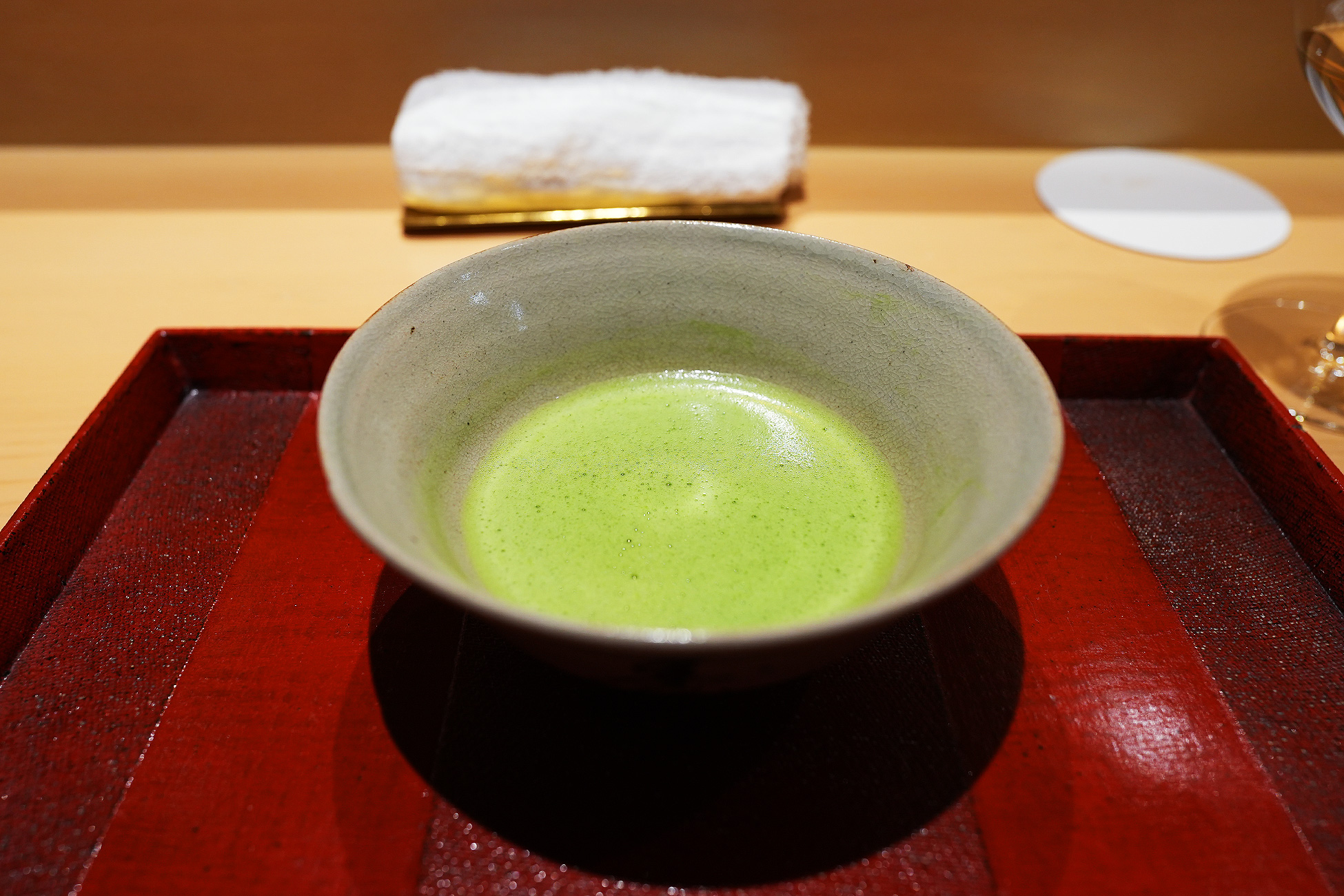 朱塗りの盆にのせた抹茶茶碗。鮮やかな緑のお抹茶が点てられている
