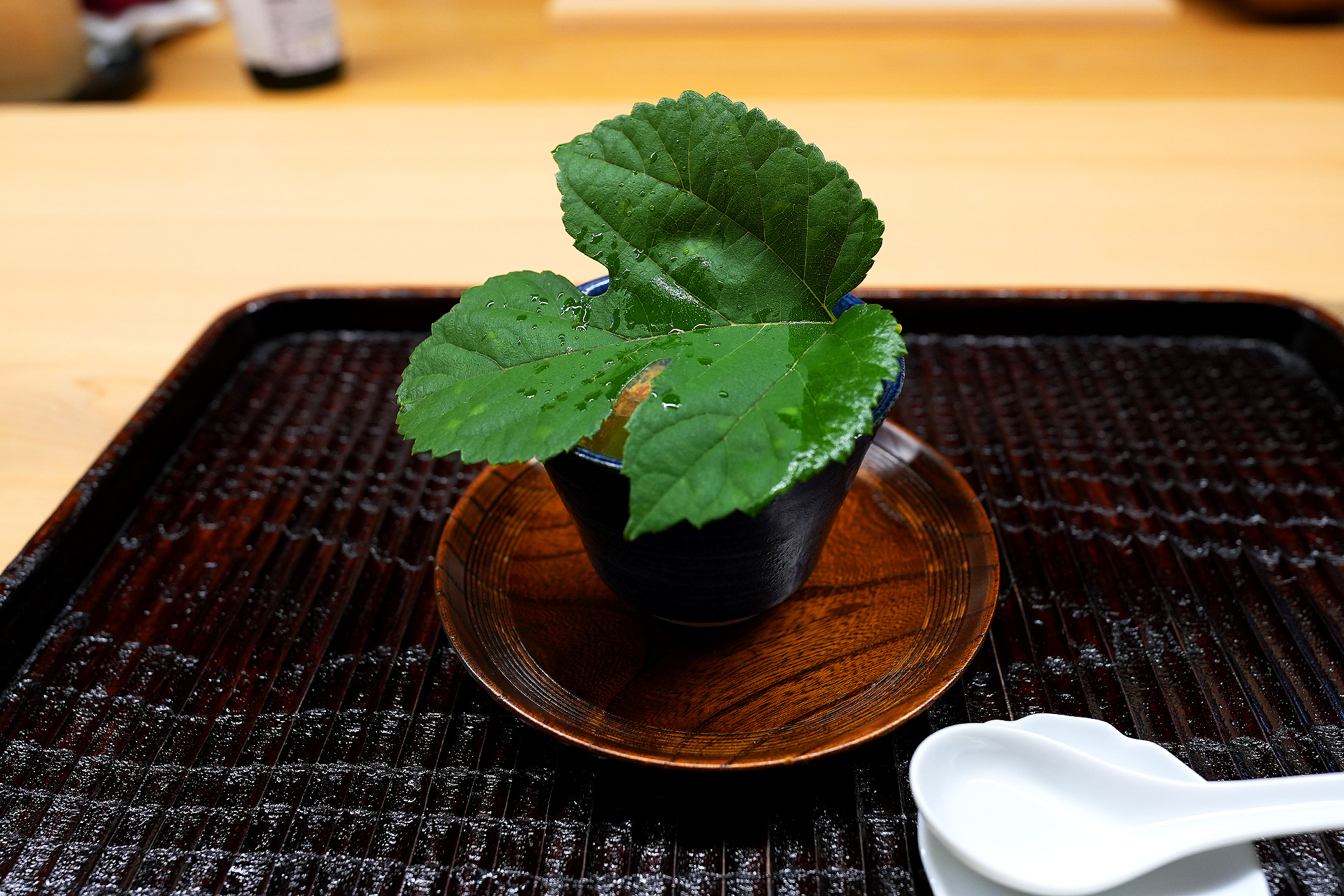 黒い器に大きな梶の葉をかぶせて出された一品。漆の盆にのっている