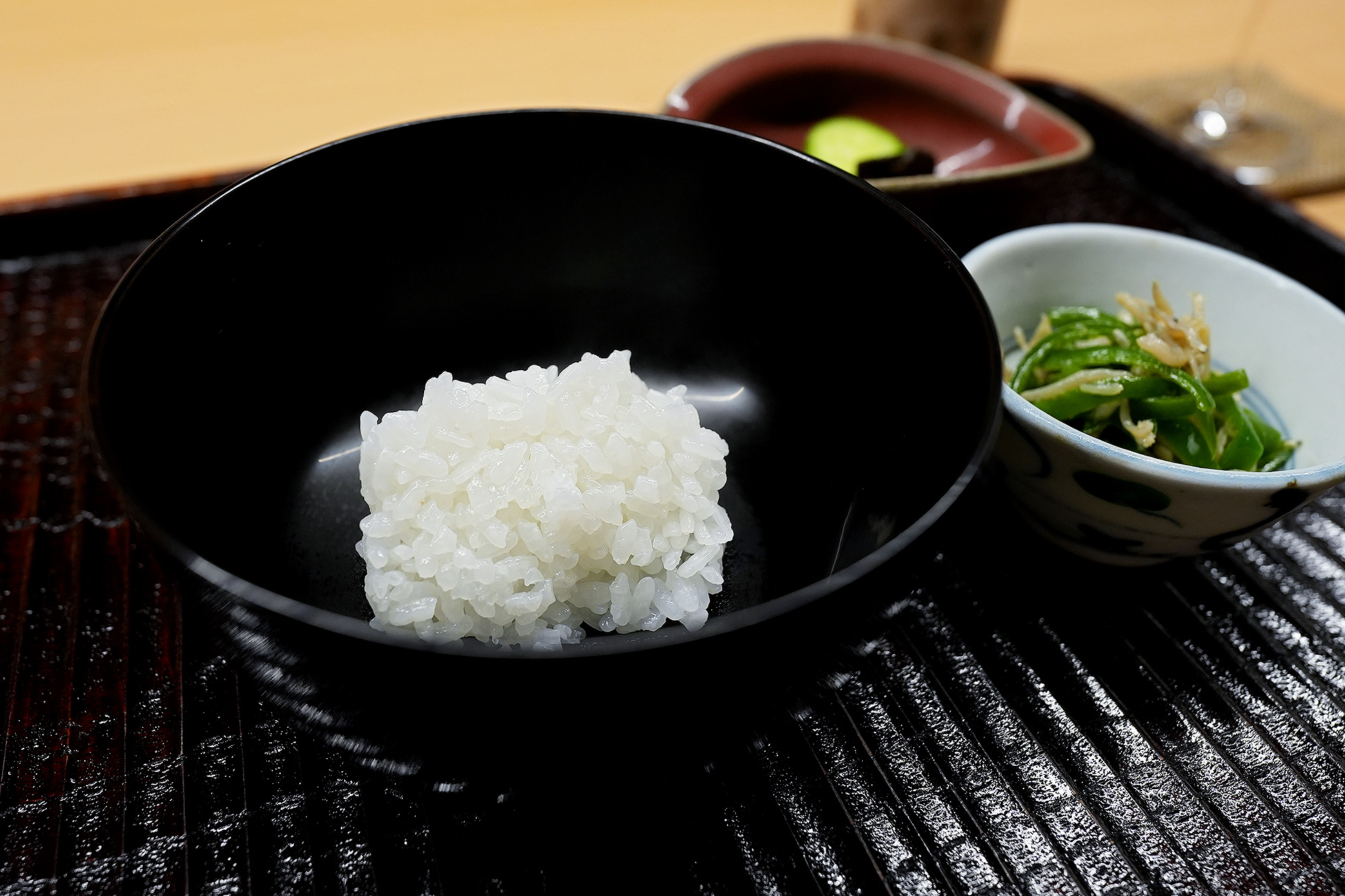 黒い椀によそった炊きたての白米。粒が大きく立っている