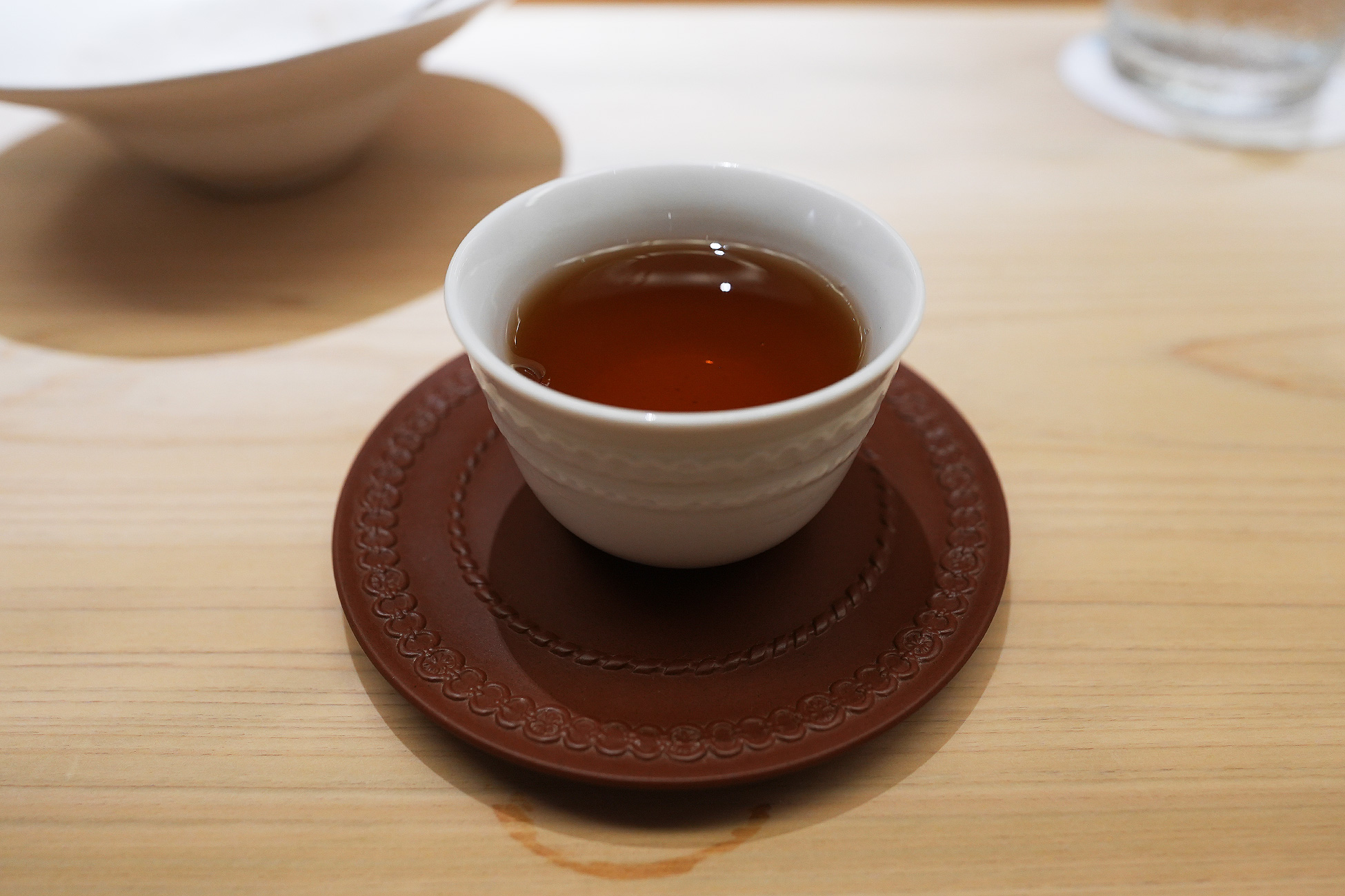 朱色の茶托にのせた白い器のダージリン茶