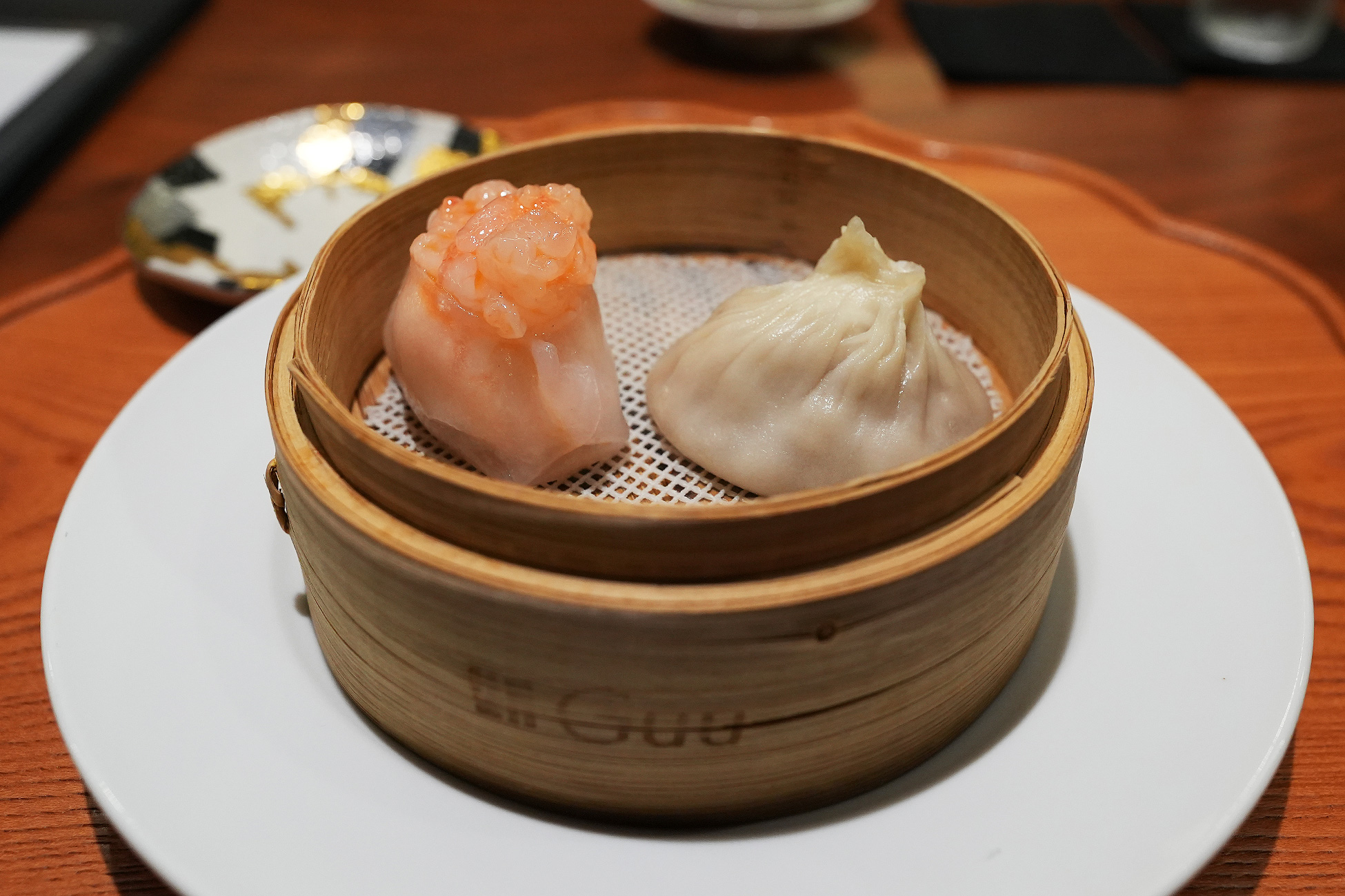 「中国菜 Guu」と焼き印された小さな蒸籠に、海老蒸し餃子と小籠包がひとつずつ入っている