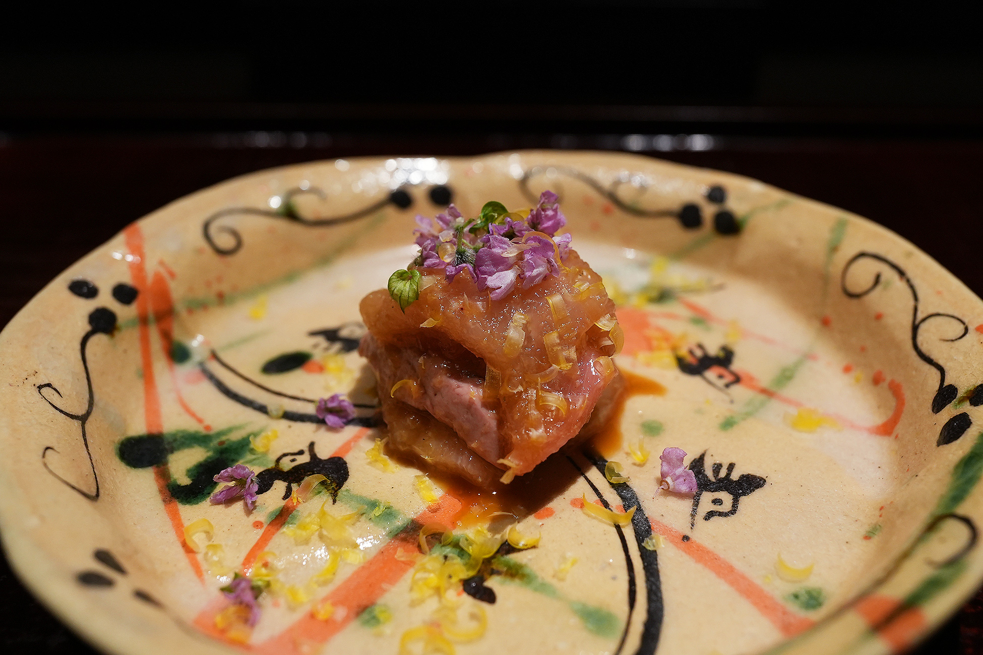 色絵の皿に、胸肉とレバーを重ねたとりわさ。黄色く削ったものがかかり、紫の小花が散らしてある
