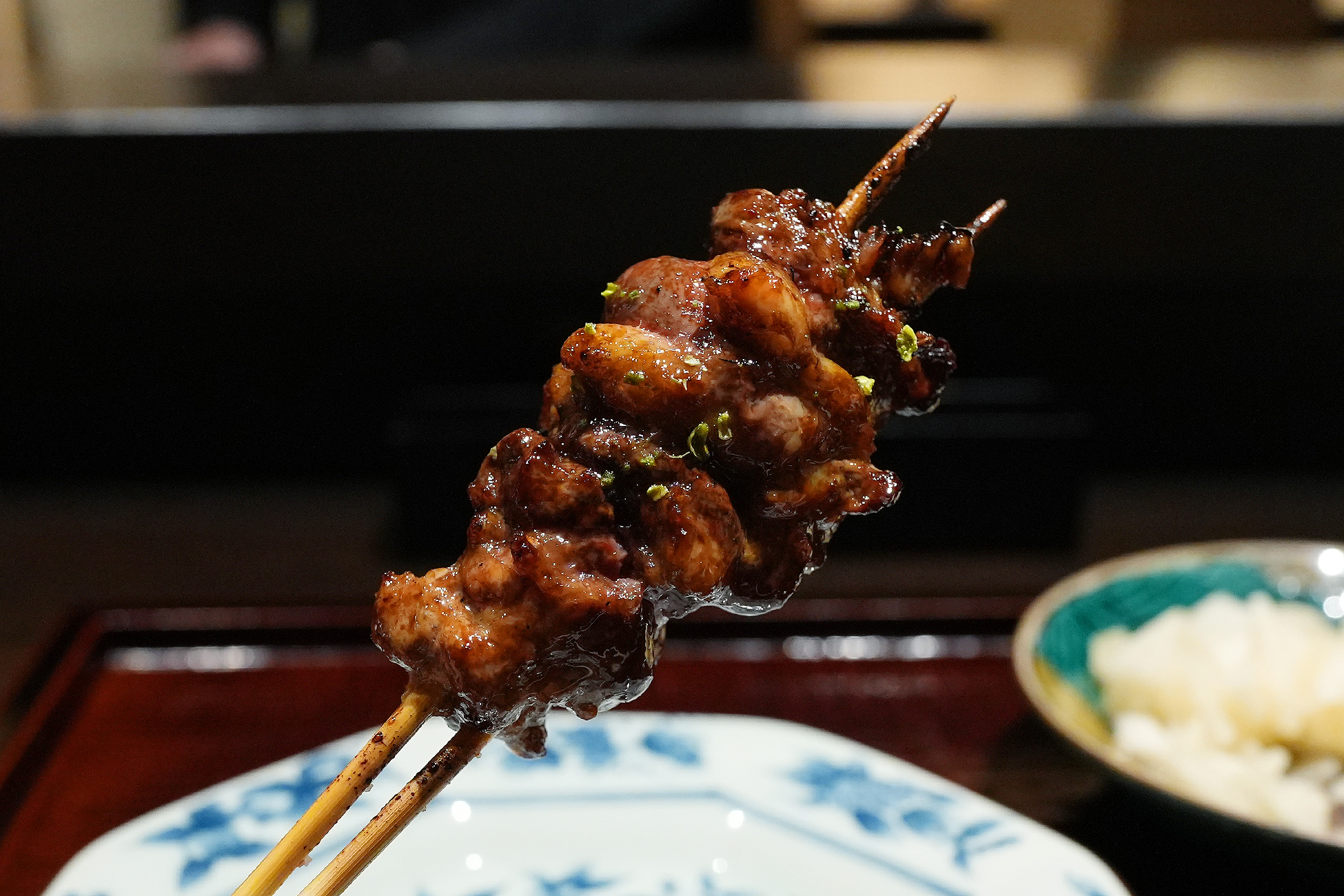 2本の串に小さな背肝がぎっしり。タレで照りが出ていて、緑色の薬味が振られている