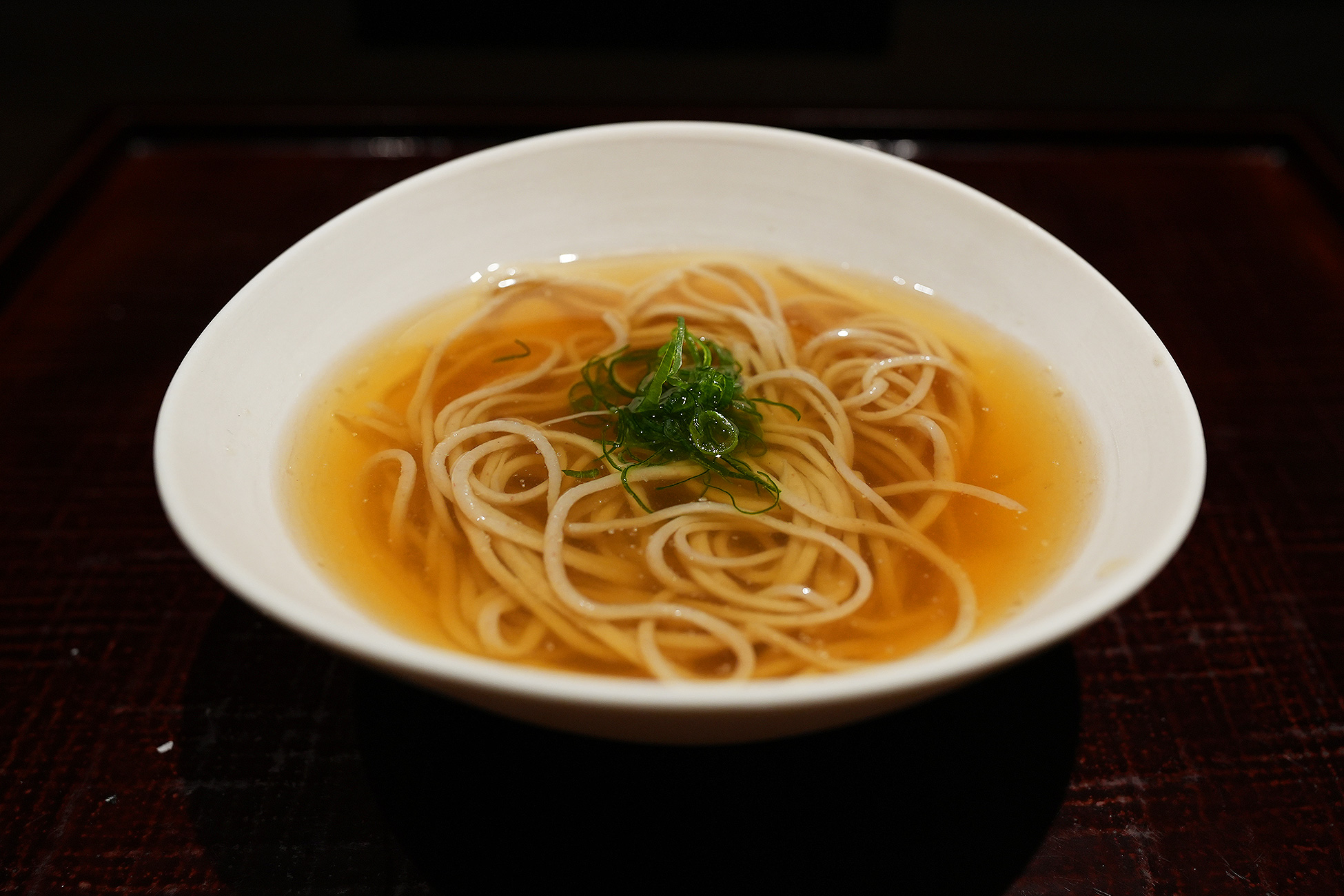 白い鉢に澄んだ琥珀色のつゆを張り、細い蕎麦を盛って刻んだ青葱をのせた鶏そば