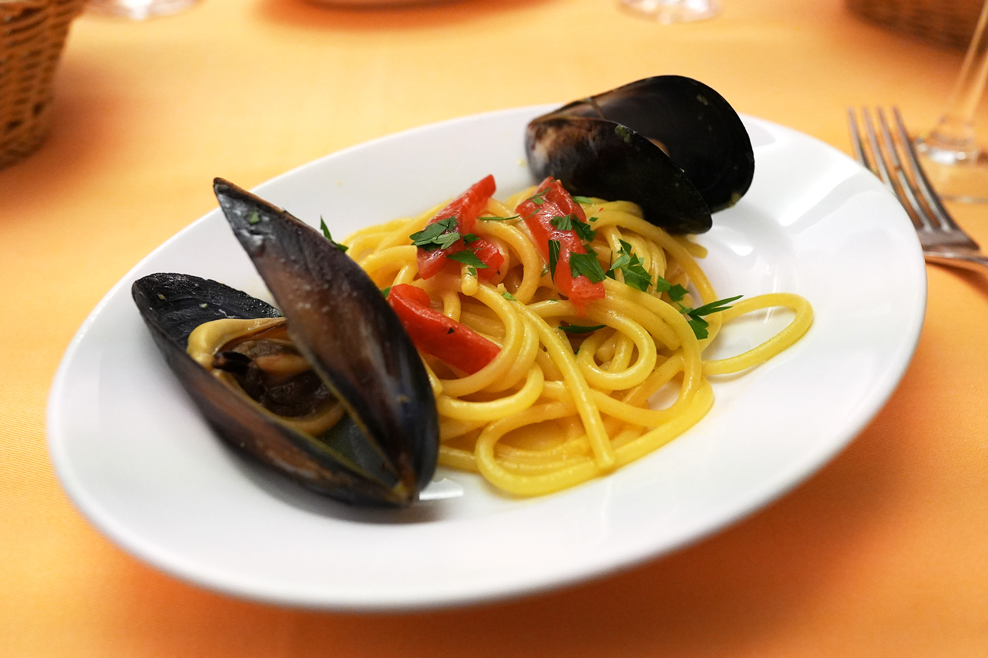 サフランで黄色く染まった太めのスパゲッティに、大ぶりのムール貝と角切りトマトをのせた一皿