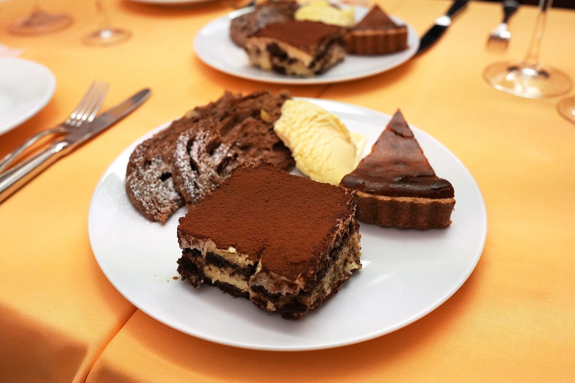 ひと皿に盛られたティラミス、チョコレートのタルト、パネットーネ、バニラジェラート