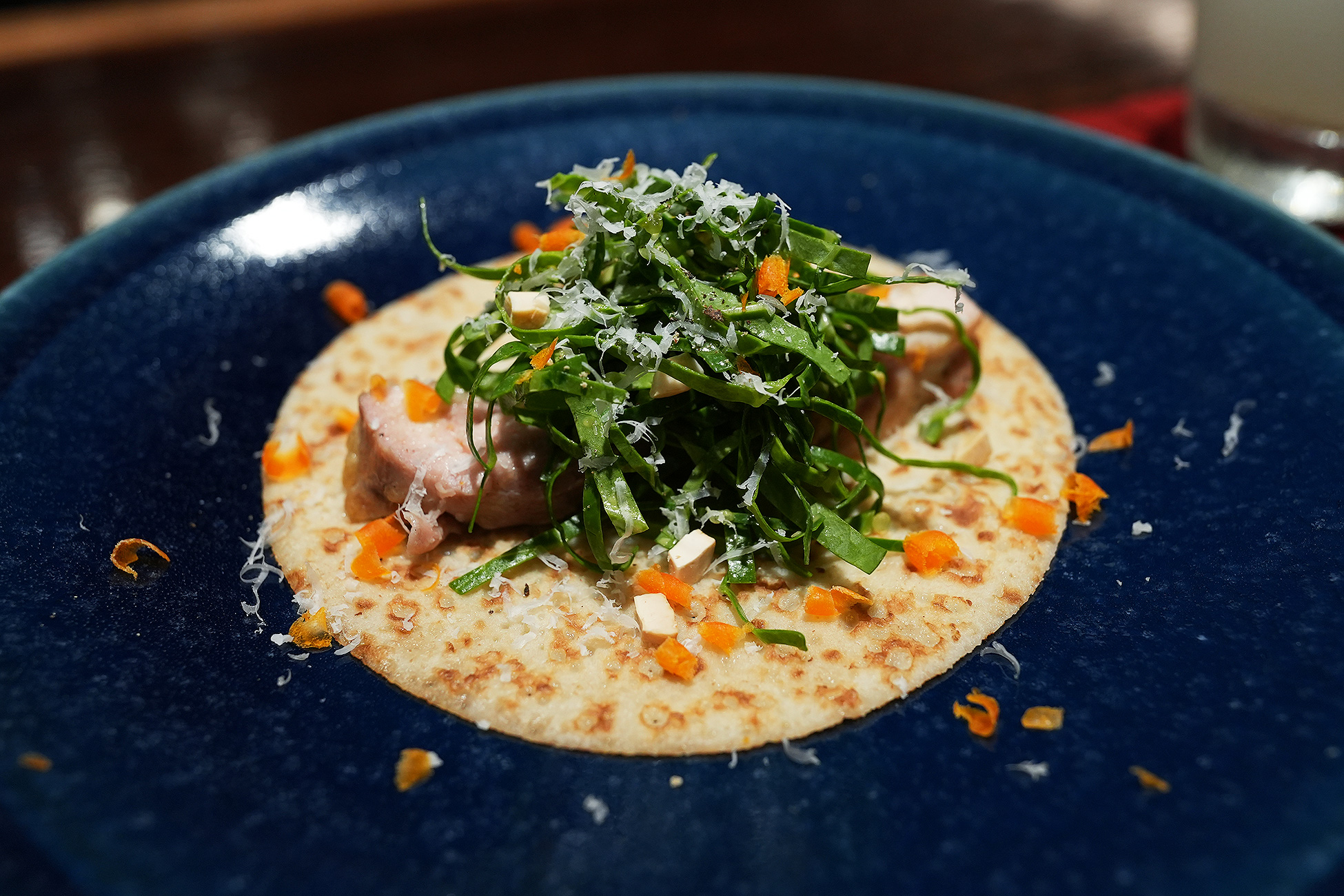 青い皿にのせた鶏のクレープ。大葉の千切りとおろしたチーズがたっぷりのり、まわりに角切りの野菜が散らしてある