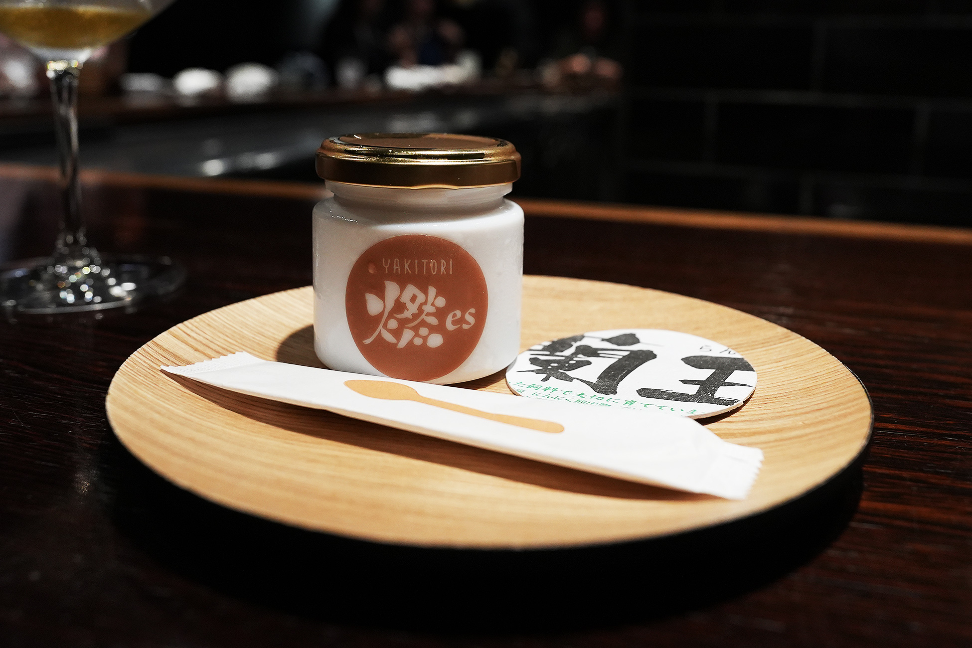 木の皿にのせた白い陶器の瓶。「YAKITORI 燃es」のロゴが入り、横に「蘭王」と書かれた紙が添えられている